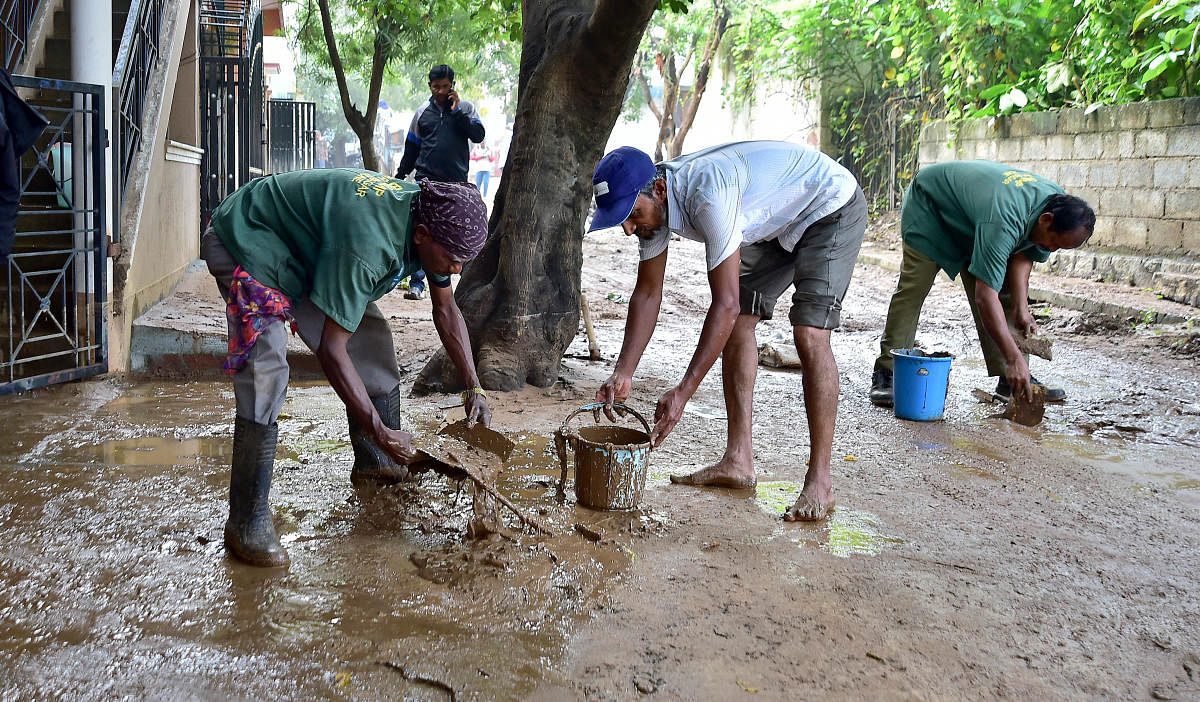 Municipal workers remove dirty water from a street on Sunday. DH PHOTO/RANJU P