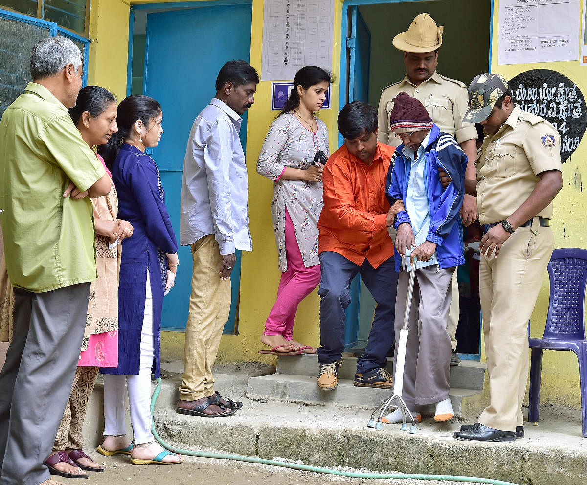 A senior citizen being assisted to come out of a polling booth after casting vote in Yeshwantput constituency. DH photo/Ranju P