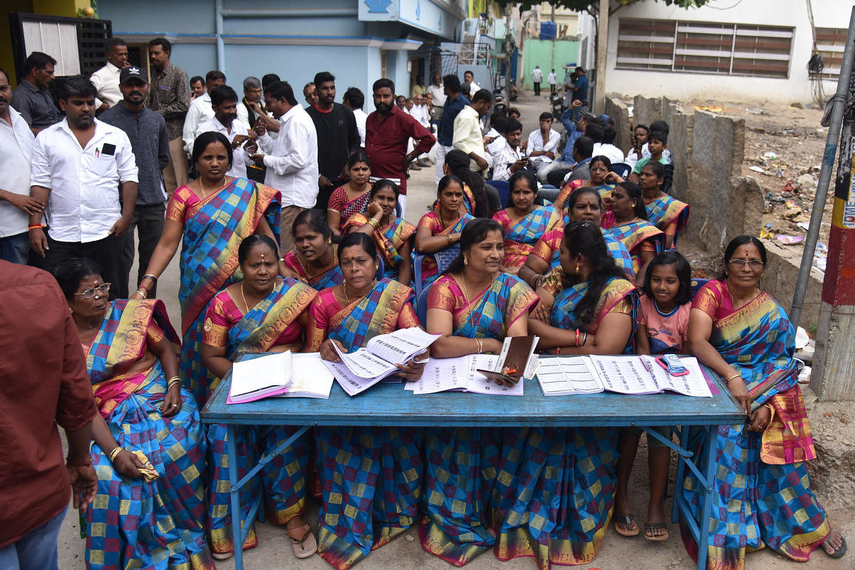 Party workers in same-coloured sarees sit at a help desk at a school in B Narayanapura, Bengaluru East.