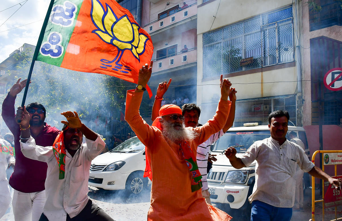 BJP supporters distribute sweets and burst firecrackers near the party’s state headquarters in Malleswaram to celebrate its victoryin the assembly bypolls on Monday. dh photos/ranju p and anup ragh t