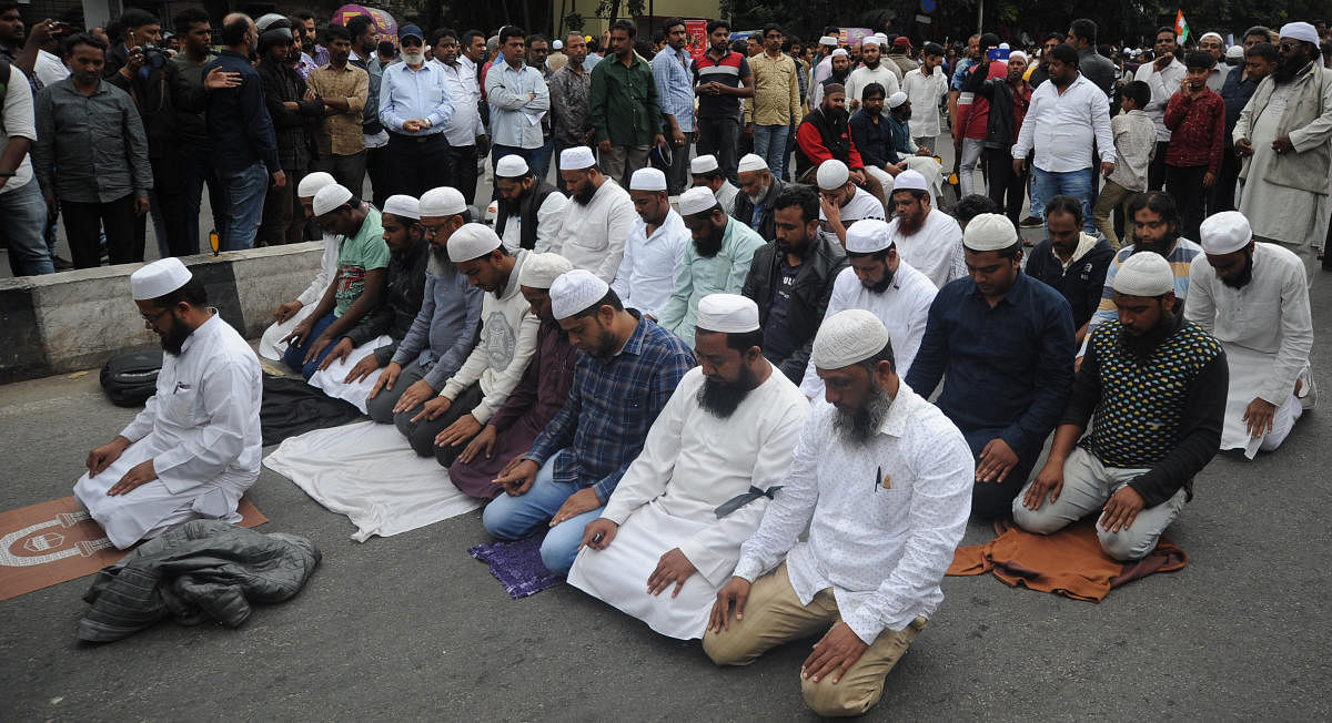 People break for prayers amid several protesters near Town Hall in Bengaluru on Thursday. People gathered in large numbers to protest against CAA. | DH Photo: Pushkar V