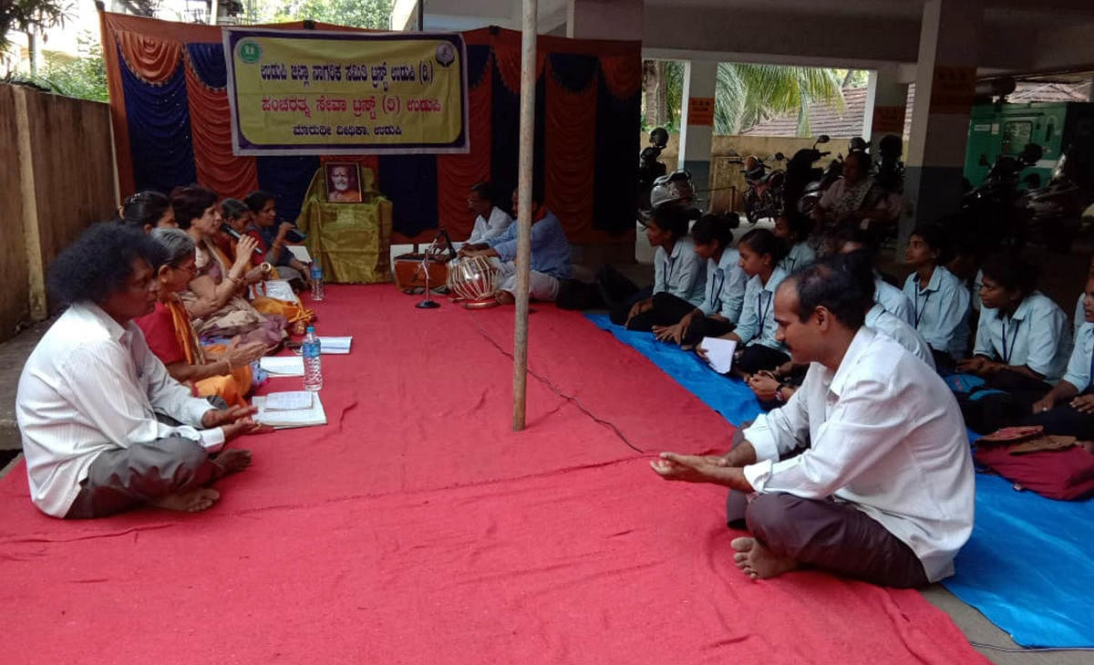 caption: Members of Nagaraika Samithi and Pancha Ratna Seva Trust sing Bhajans and offer prayers seeking a speedy recovery for the senior Pejavar pontiff in Udupi on Friday.