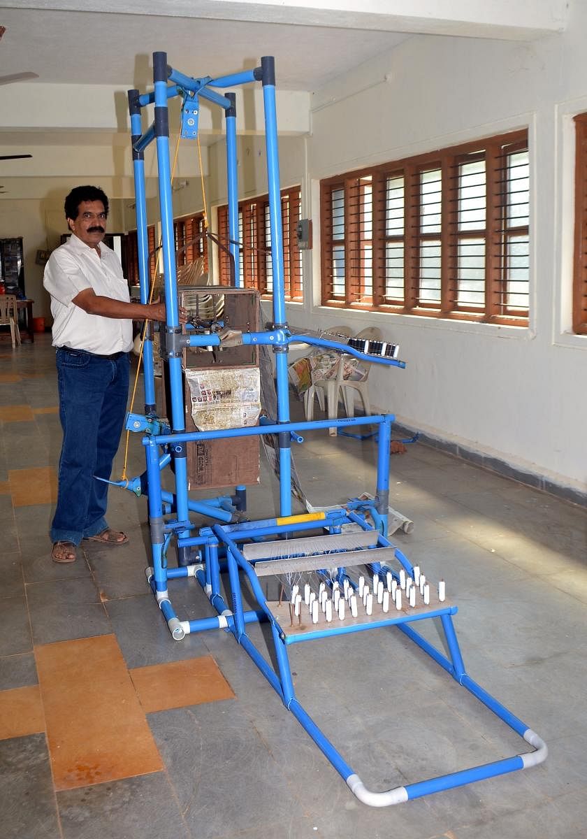 Joint Director of District Industries Centre Dhananjay Hegde with the demo machine developed by him to prepare an improvised paper bag.