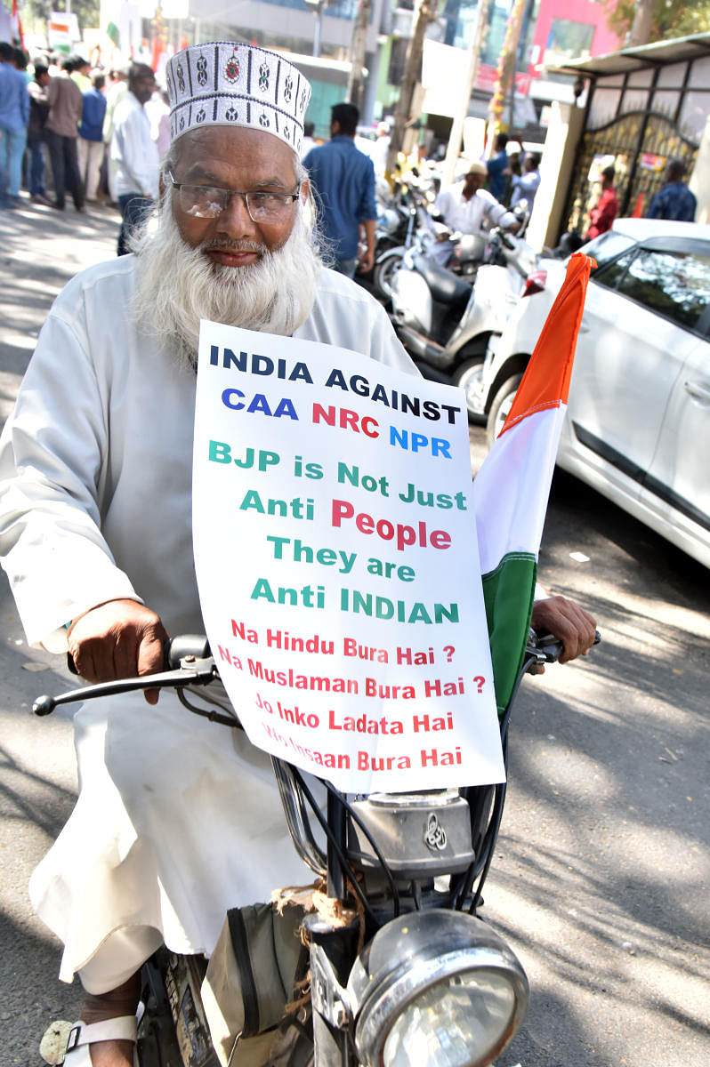A man carries an anti-CAA placard on his moped during a rally in Pulakeshinagar on Monday. DH PHOTO/JANARDHAN B K