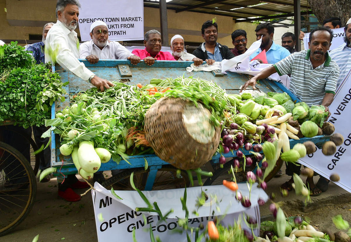 Vendors dump vegetables on the road in protest against the delay in permitting them to occupy shops at the newly constructed market complex in Cox Town. DH photos/Irshad Mahammad 