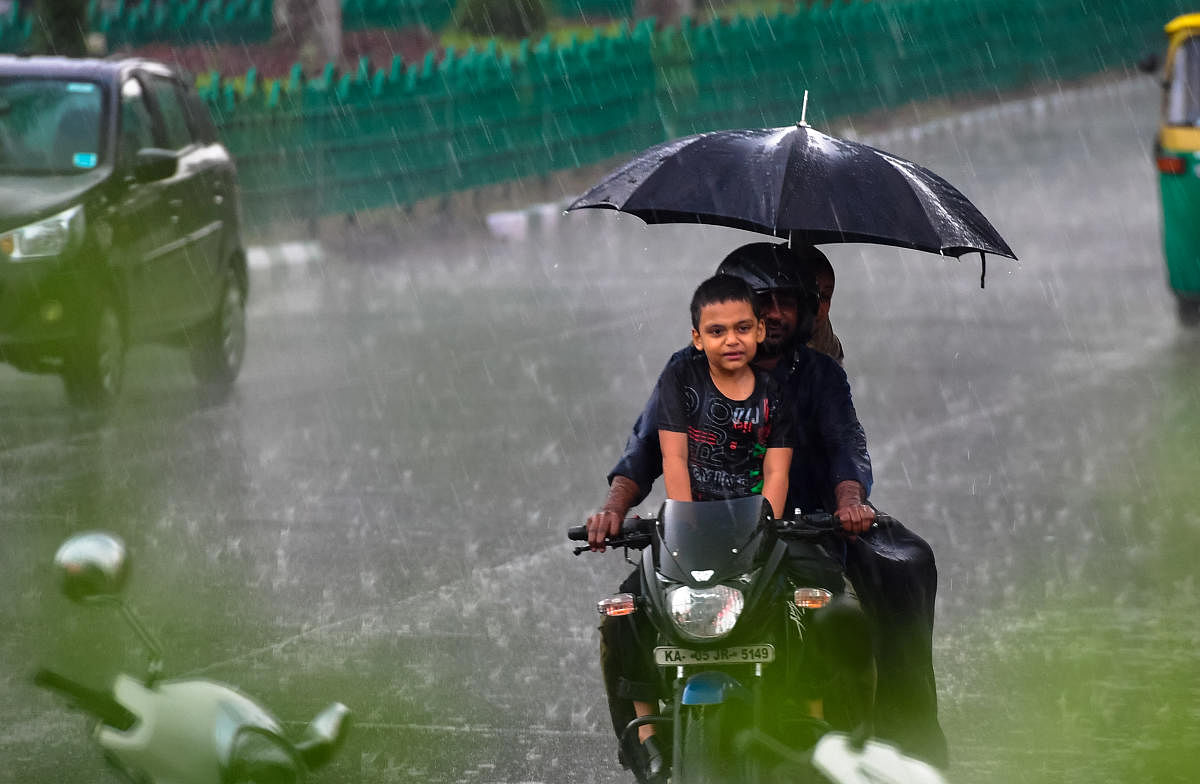 A family braves heavy rains on Ambedkar Veedhi.DH photo/KRISHNAKUMAR P S