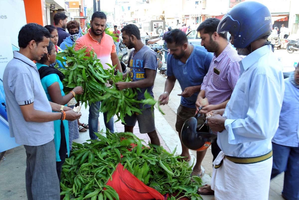 People purchase mango leaves in the town in view of Ugadi festival.