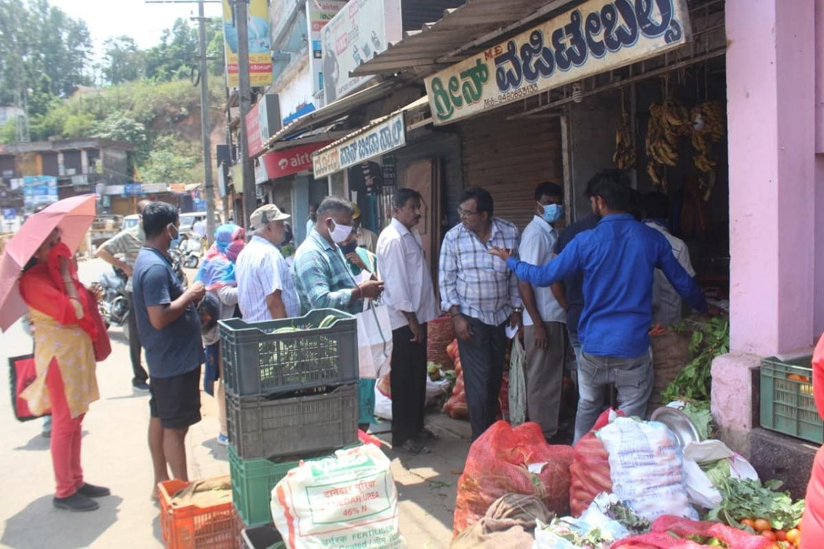 People wearing masks queue up at a shop for purchasing vegetables. 