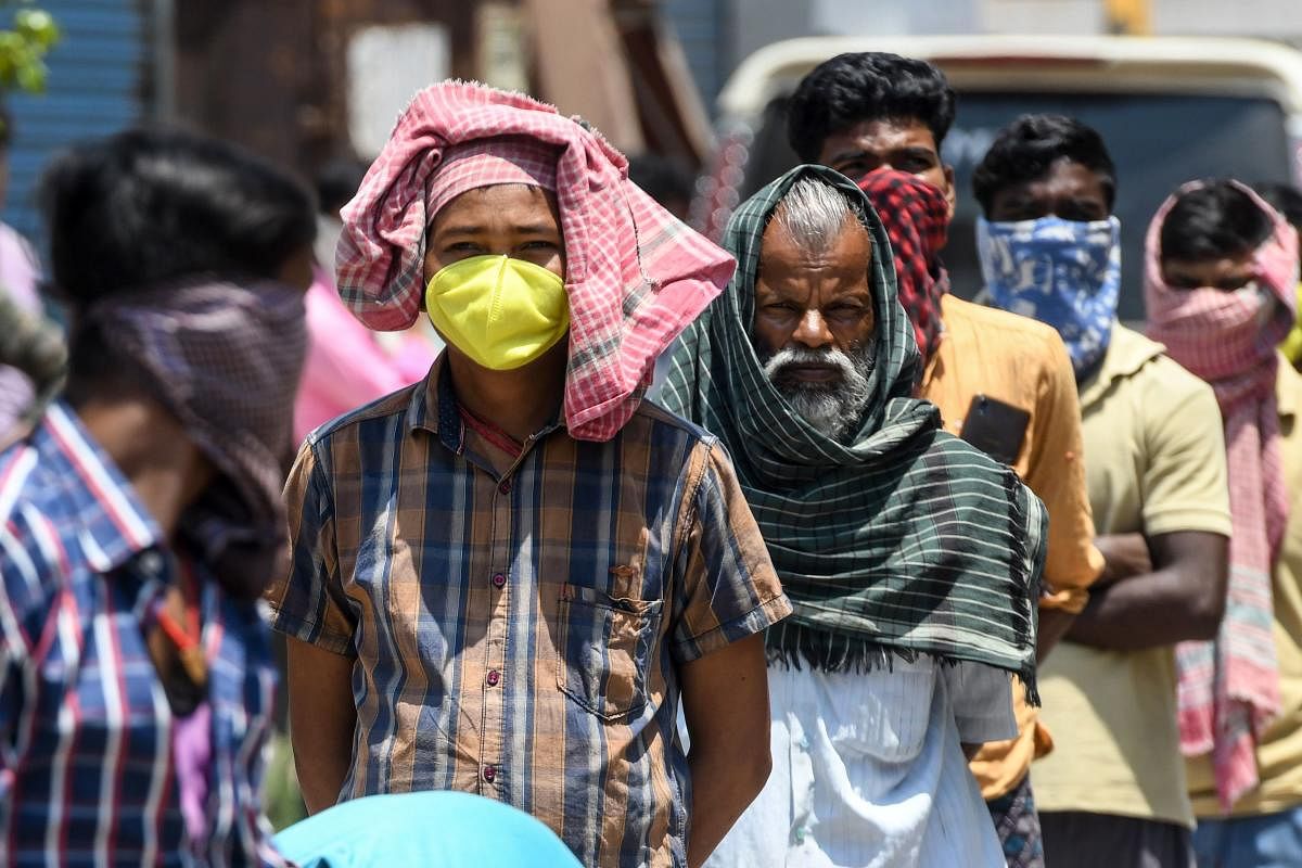 Migrant labourers travel on a crowded tempo in Bengaluru. Workers maintain social distancing as they receive food packets in Chennai. Photos by: B H Shivakumar, AFP