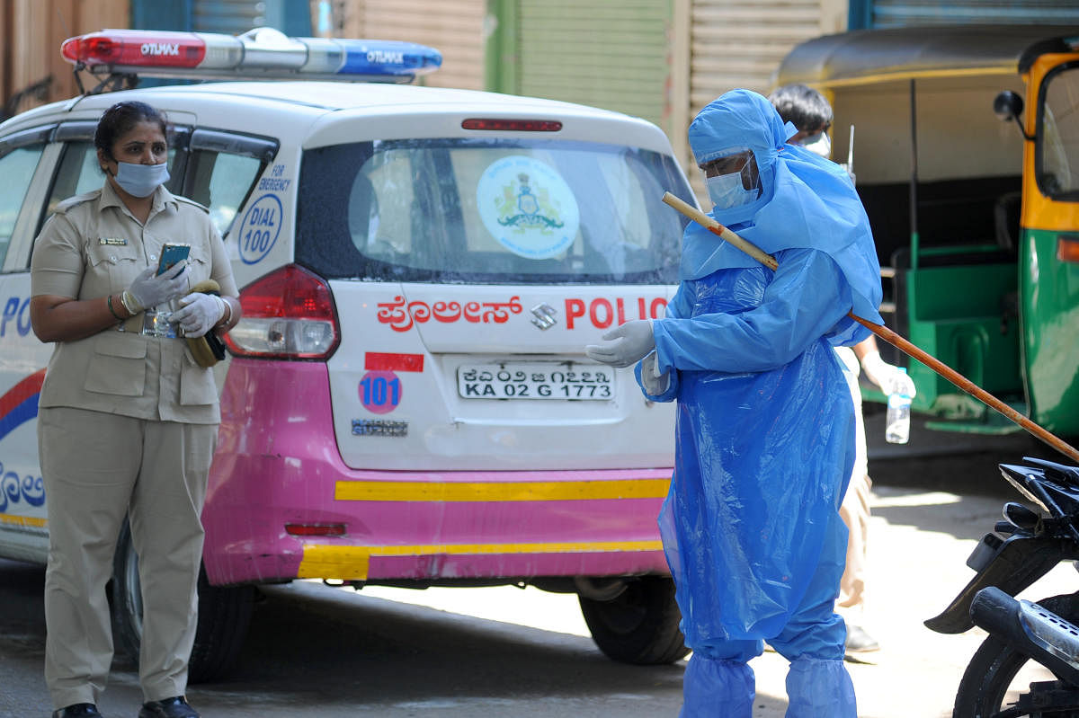 A policewoman and a healthcare worker in protective gear are seen in Tipu Nagar, which has been cordoned after a Covid-19 patient died there. DH PHOTO/PUSHKAR V