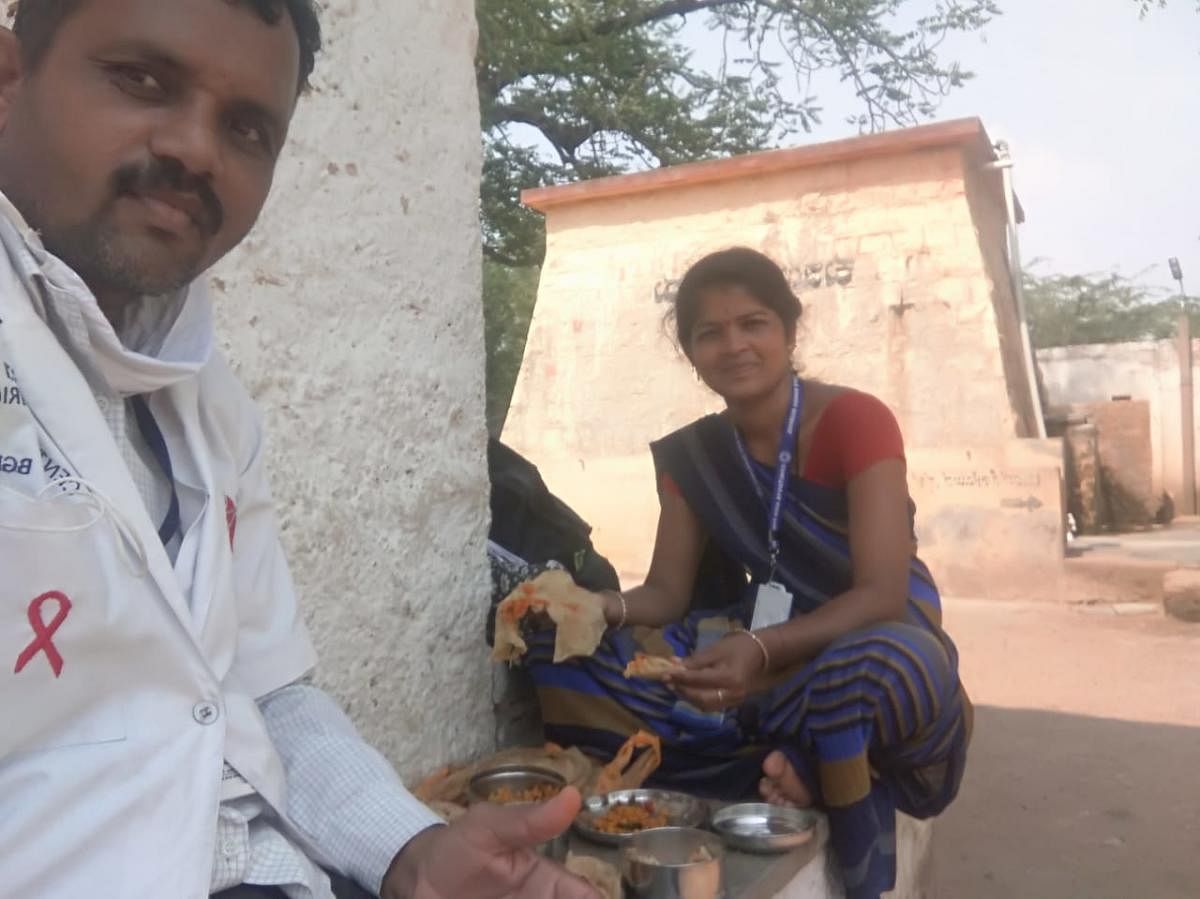 A counsellor and a community support centre staffer have lunch on a field in Bagalkot during the supply of medicines.