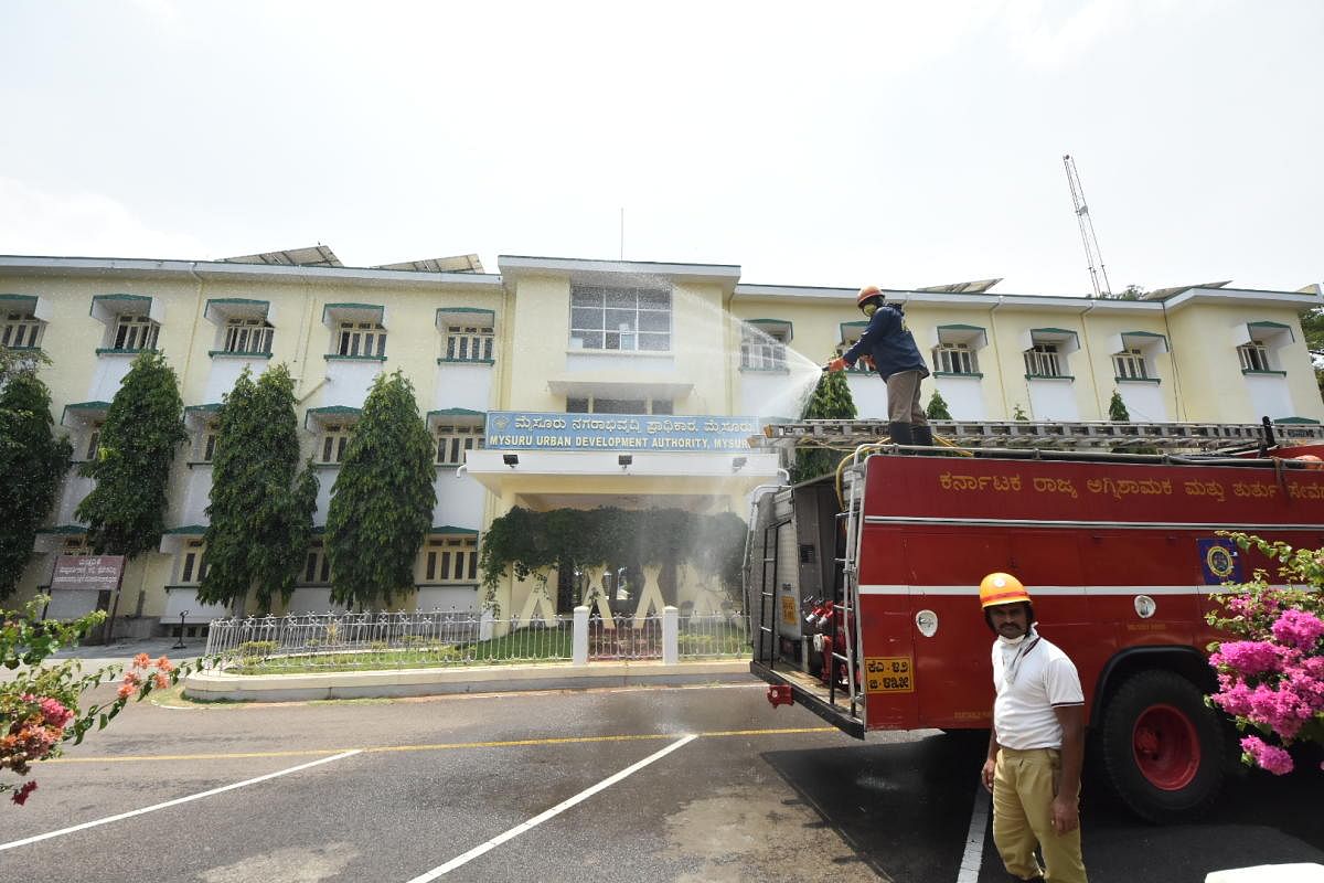 Fire and Emergency Services personnel spray disinfectant to Mysuru Urban Development Authority (MUDA) Office, in Mysuru.    