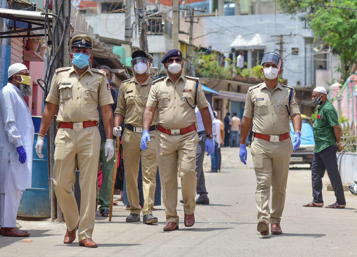 Supporters of BBMP corporator Nazima Khanam stage a protest in Tipu Nagar on Sunday. (R) Policemen stand guard to avoid untoward incidents. DH PHOTOS/Irshad Mahammad
