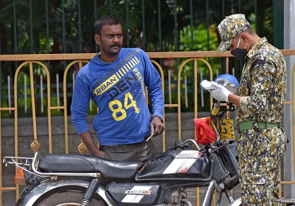 A BBMP marshal fines a motorcyclist for not wearing a mask on Thursday. DH photo/M S MANJUNATH