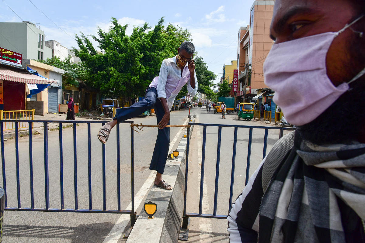 A man jumps a barricade in Kalasipalyam on Tuesday. DH photo/B H SHIVAKUMAR