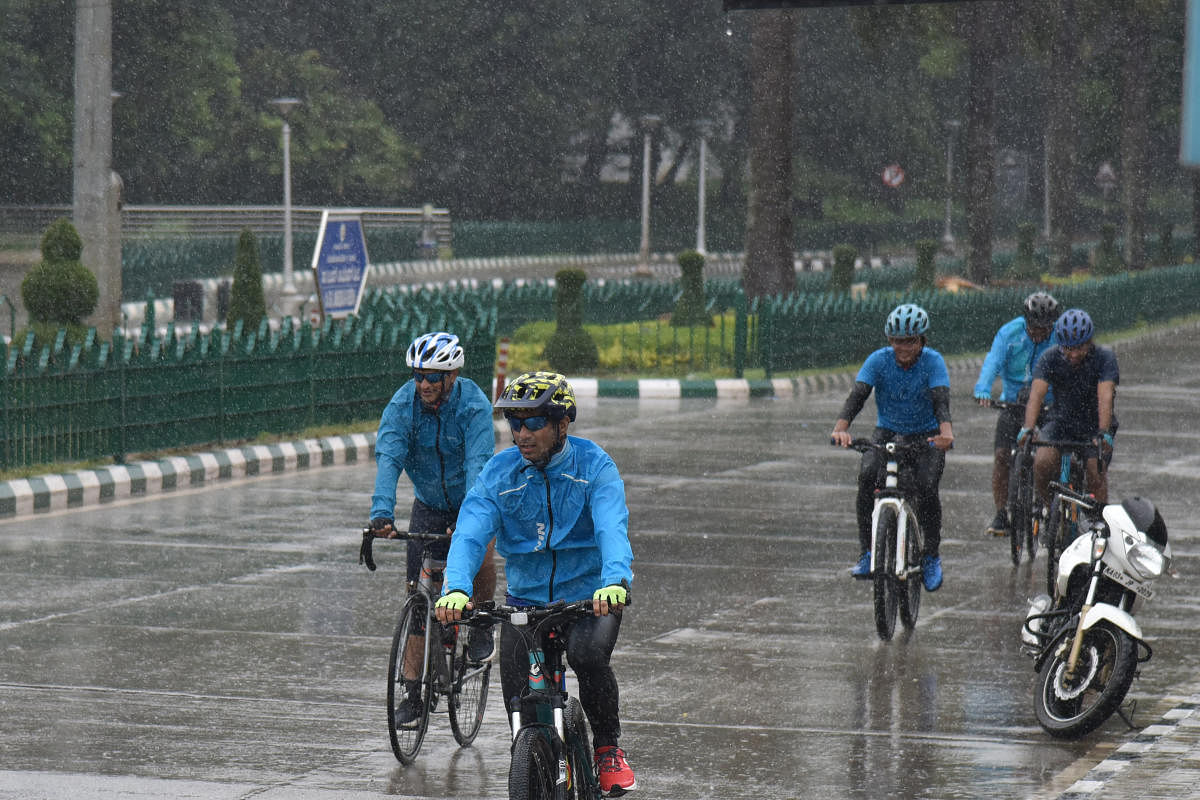 Cyclists enjoy the rain at BR Ambedkar Veedhi on Sunday. DH Photo/S K Dinesh 