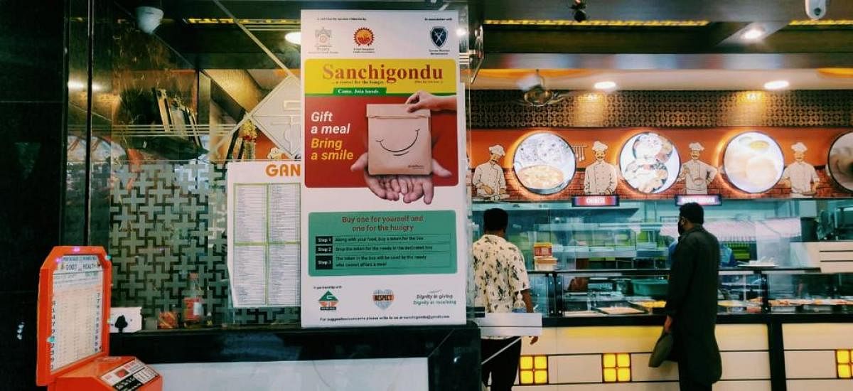 A customer at a hotel in Bengaluru donates a meal to the needy under the 'Sanchigondu' programme. (R) The Sanchigondu banner has been put up at a few eateris.