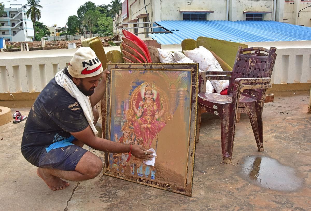 A resident cleans muck from the portrait of a deity in Hosakerehalli on Saturday.DH PHOTOS/IRSHAD MAHAMMAD
