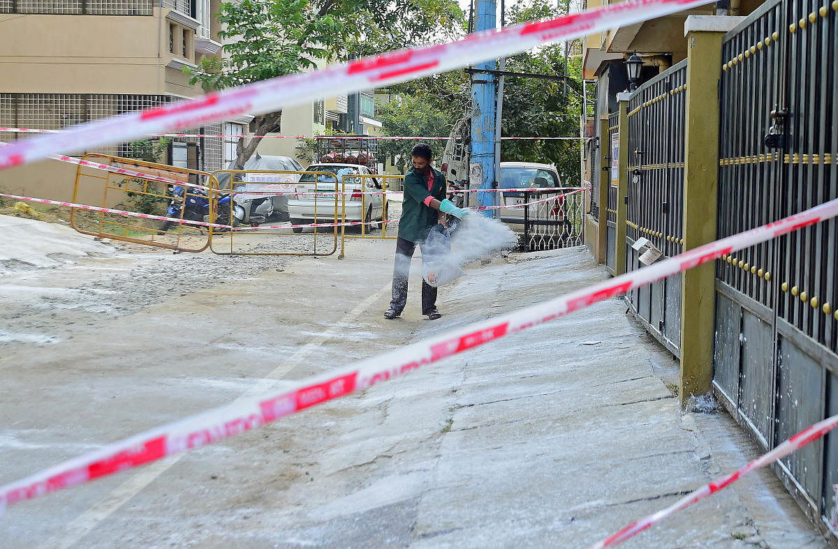 A worker sprays a disinfectant outside the apartment complex. DH PHOTO/RANJU P