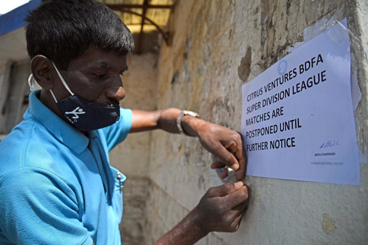 A staff posts a note stating that the Super Division league matches have been postponed until further notice at the Bangalore Football Stadium on Tuesday. DH Photo/Pushkar V