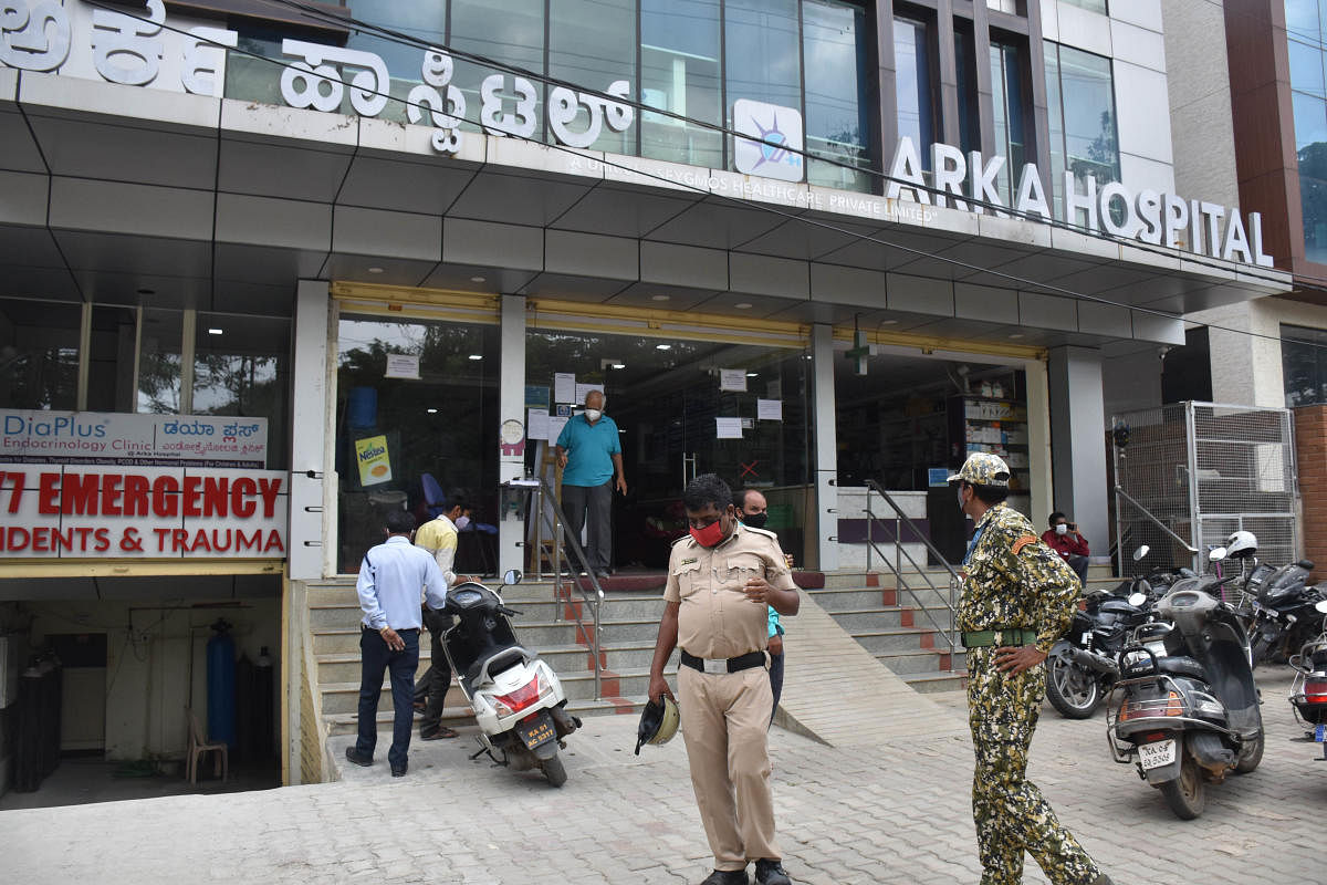 A policeman and a BBMP marshal stand outside Arka Hospital, where two patients reported died due to a shortage of oxygen, in Bengaluru on Tuesday. DH PHOTO/Janardhan B K