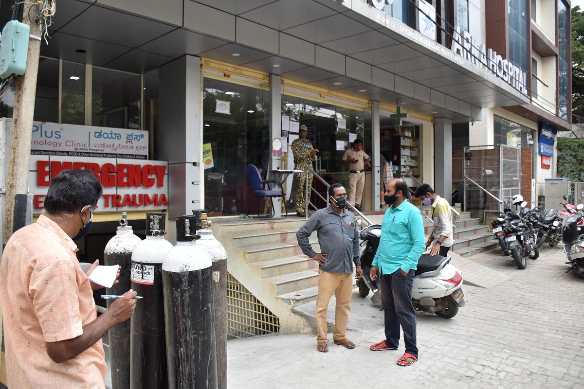 A policeman and a BBMP marshal stand outside Arka Hospital, where two patients reported died due to a shortage of oxygen, in Bengaluru on Tuesday. DH PHOTO/Janardhan B K