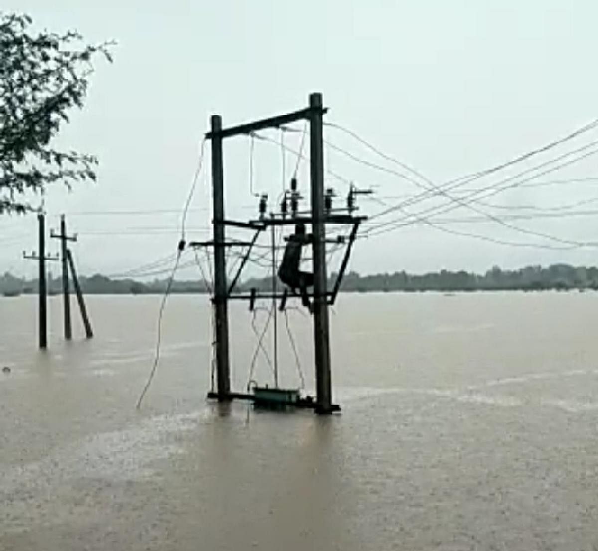 A Hescom lineman swims to reach an electricity pole marooned in tank water at Chikkonati near Hamsabhavi in Haveri district on Saturday, retrieves the electricity supply by repairing the power line, and swims back to safety. Credit: DH Photo