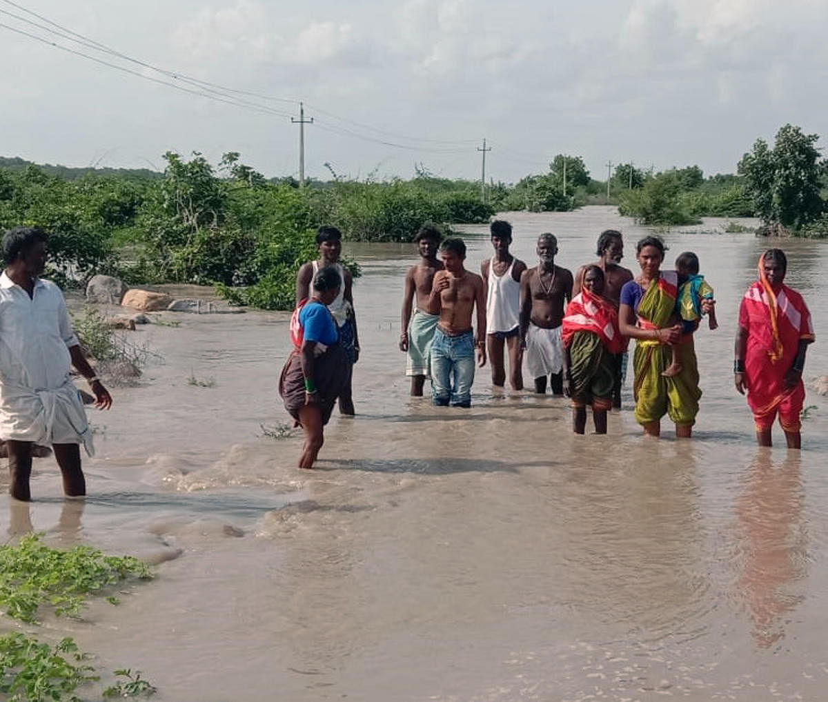 Villagers walk in flood to save those stranded at Tavadagaddi in Lingsugur taluk in Raichur district. Credit: DH Photo