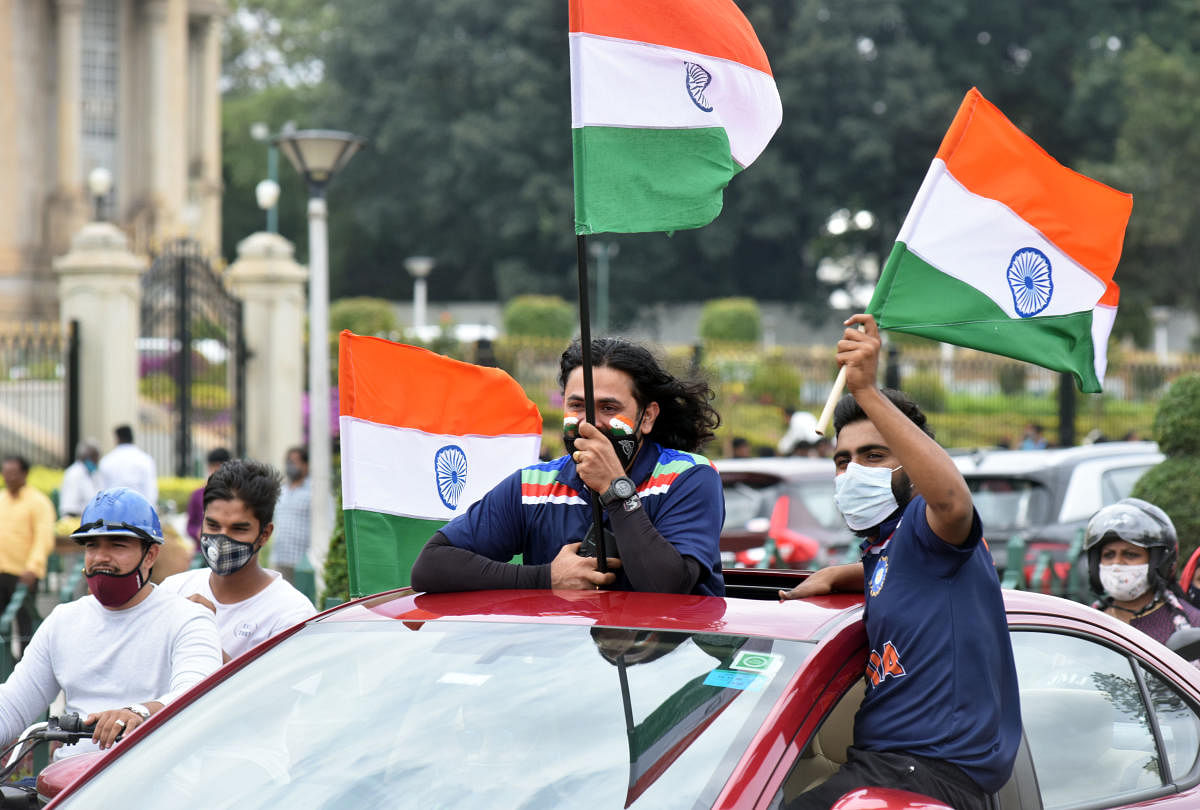 Two men raise the Indian flag from a car on Ambedkar Veedhi on Sunday. Credit: DH Photo/Anup Ragh T