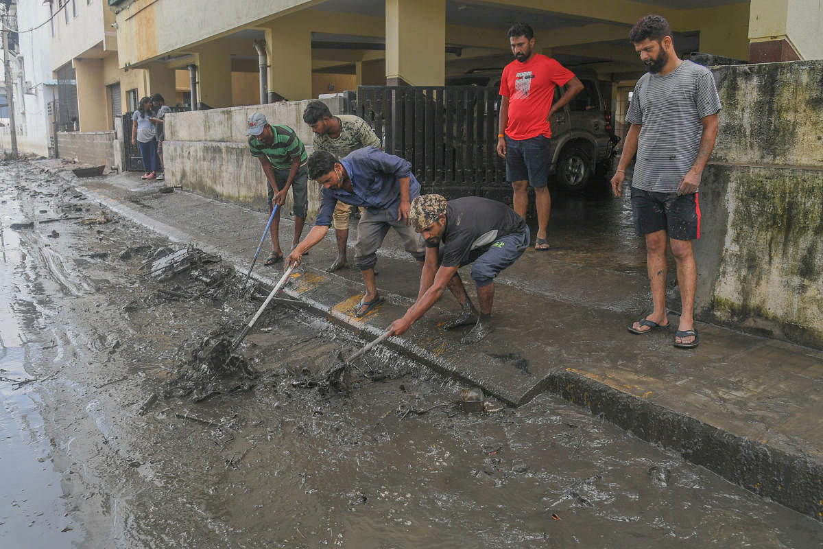 Residents come together to clear silt from their layout at Rajarajeshwari Nagar on Monday following a heavy downpour on Sunday. DH Photo/S K Dinesh