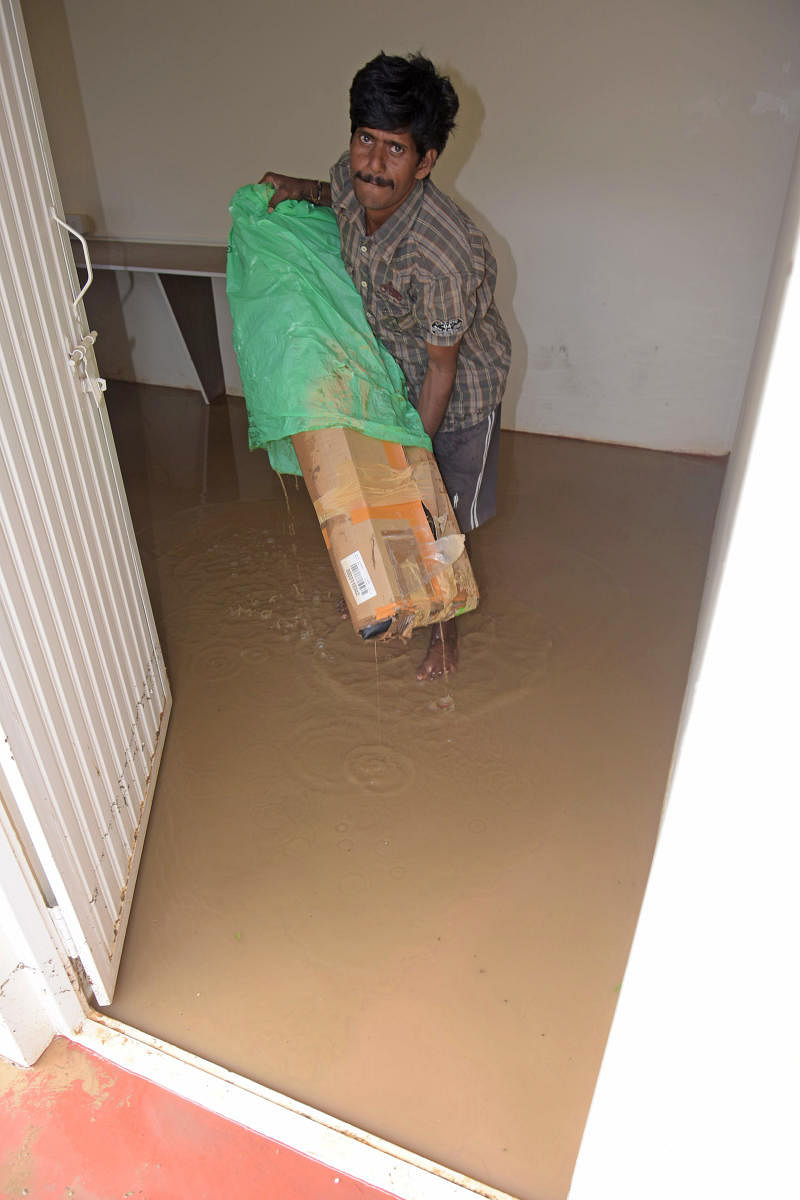 A man tries to salvage belongings at his waterlogged home in Kothanur. Credit: DH Photo/Pushkar V