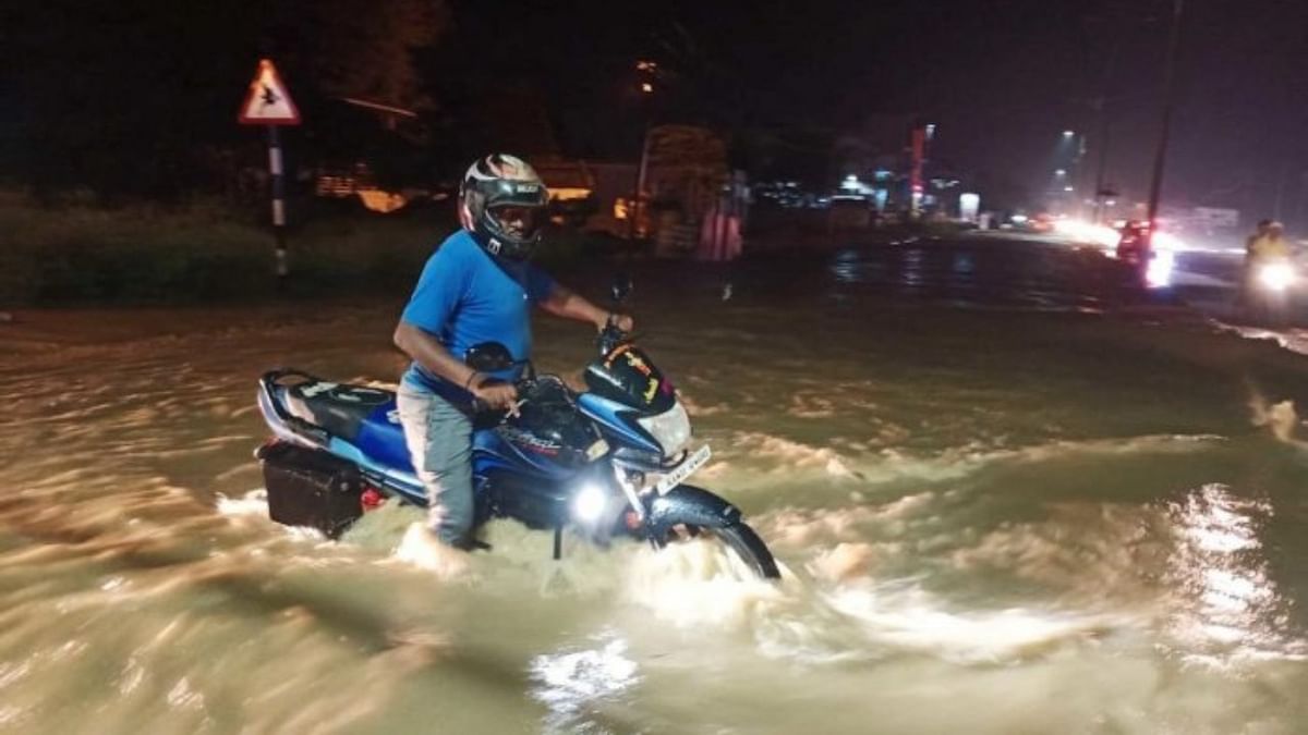 A motorcyclist struggles to cross a flooded road in Haveri.