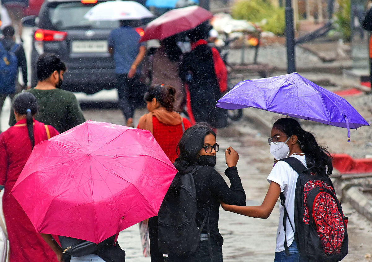 People take cover amid the showers at Commercial Street. DH PHOTO/PUSHKAR V