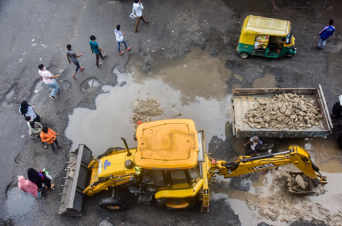 BBMP workers fill the potholes at KR Market with gravel on Friday. A large majority of roads in Bengaluru are riddled with potholes. DH PHOTO/ANUP RAGH T