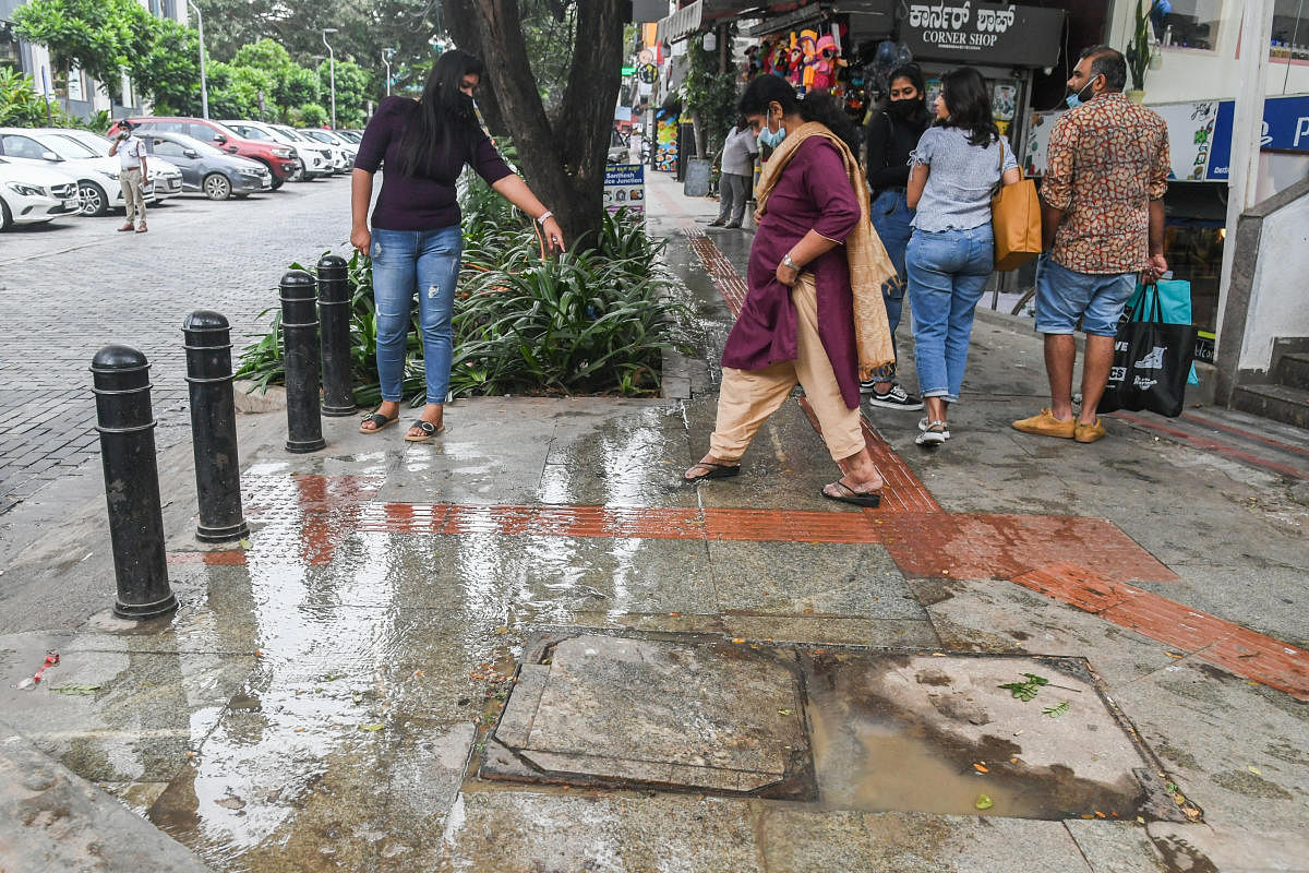 People waded through dirty water on Church Street as sewage water overflowed from a manhole on Saturday. Passersby said the stench was unbearable. DH PHOTO/S K Dinesh