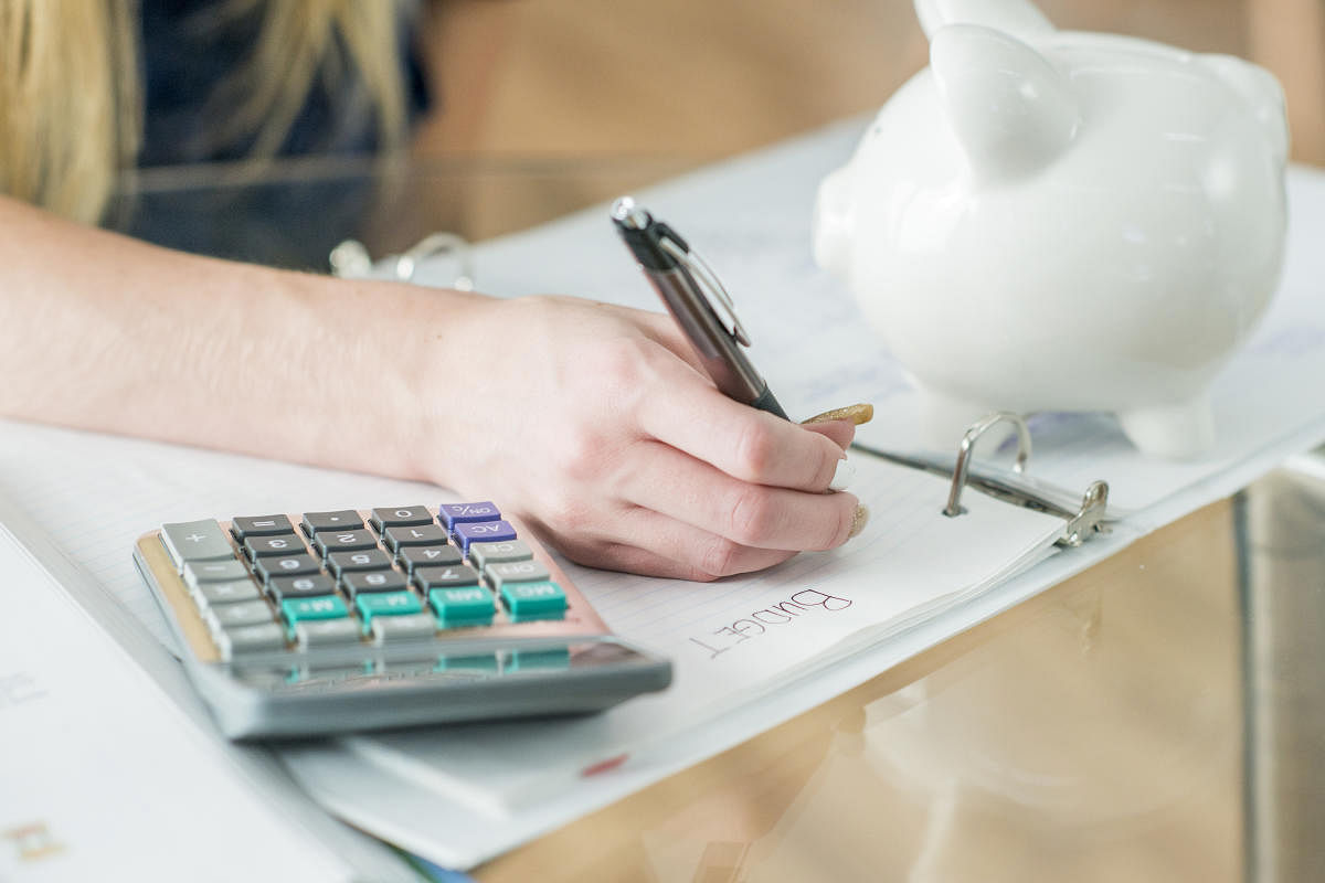 A Caucasian teenage girl is indoors. She is wearing casual clothing. She is writing in her binder. A calculator is on the table.Writing In Binder stock photo.