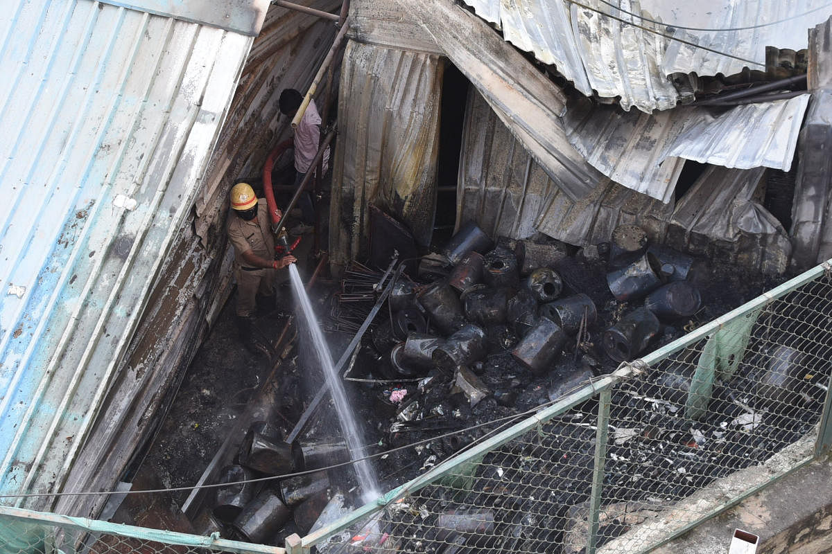 A fireman extinguishes flames from chemical canisters at the metro storehouse in Bamboo Bazaar, Shivajinagar, on Saturday. Credit: DH Photo/Pushkar V