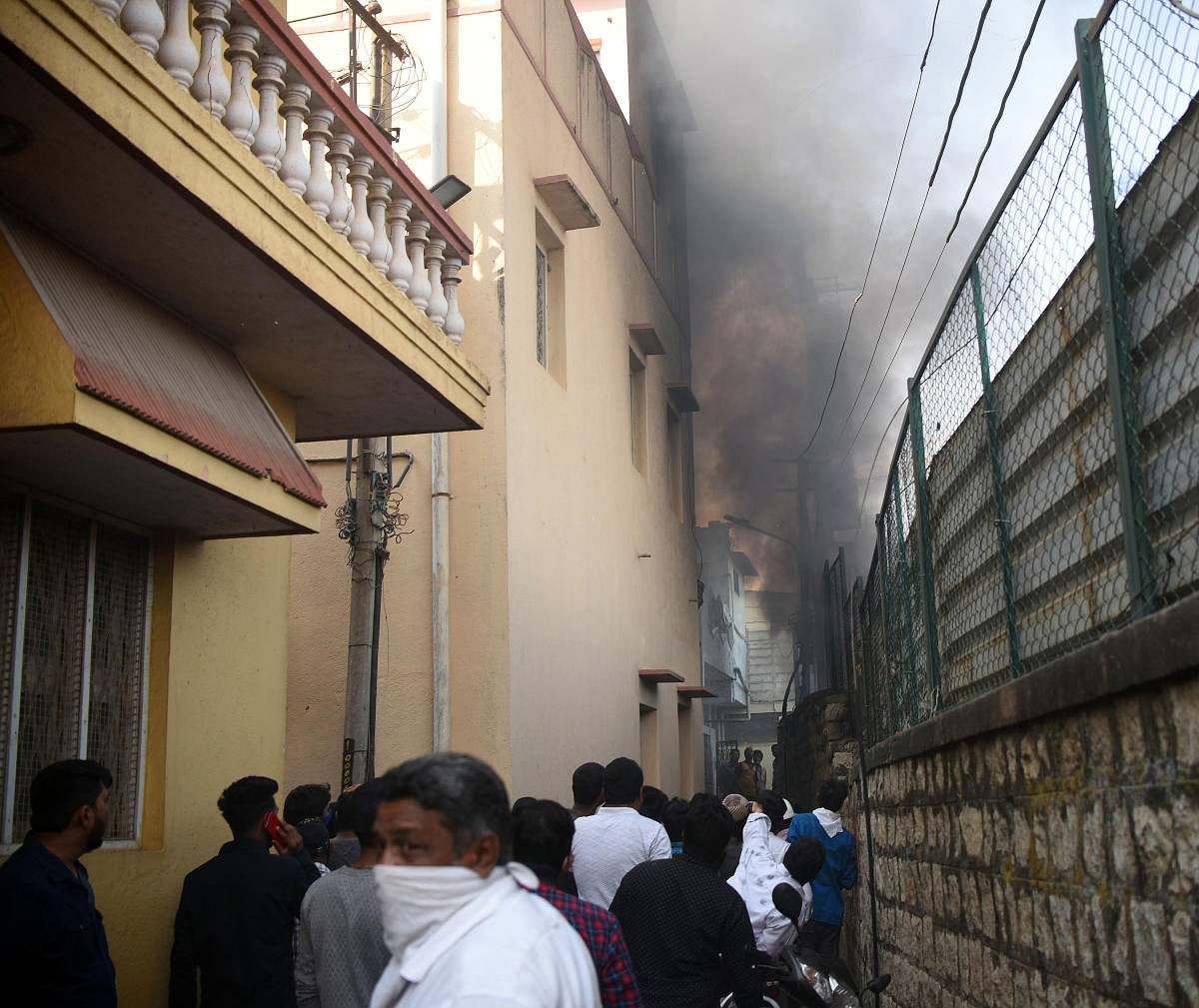 Smoke rises from the metro site in Bamboo Bazaar, Shivajinagar, on Saturday. The site boundary is separated through a small alley from a row of tightly packed houses in the densely populated locality. Some houses suffered damage following the fire. Credit: DH Photo/Pushkar V