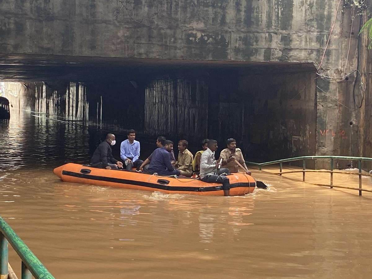 People trapped beneath the flooded underpass are rescued with the help of a dinghy in Ramanagara. Credit: DH Photo/S K Dinesh