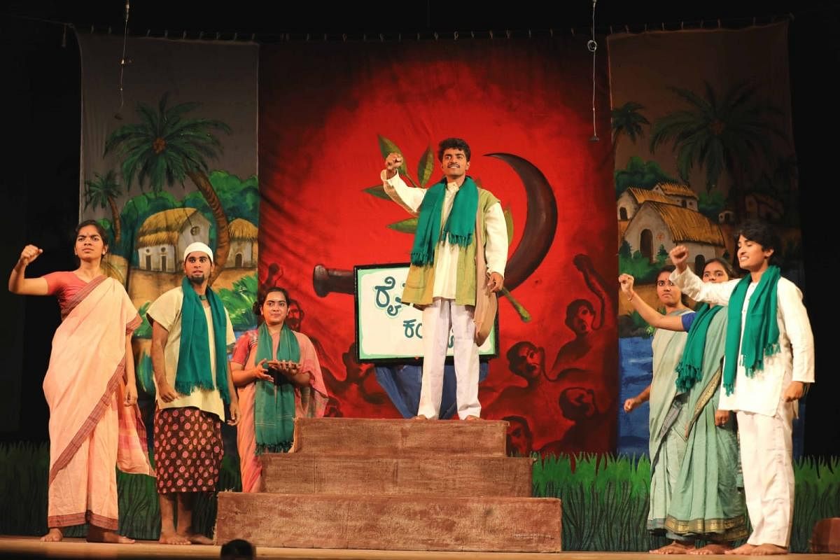 A scene from the play ‘Chirasmarane’, directed and stage-designed by Maltesh Badiger. The play deals with farmers protesting against the bureaucracy. The backdrop shows symbols and visuals of a village, and the grass is created with foam. Credit: Special Arrangement