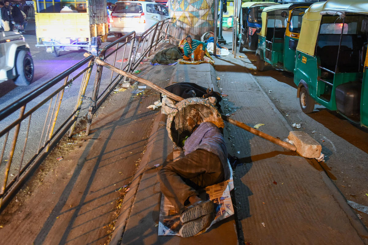 The Mysuru Road flyover and footpaths in its vicinity are used by many to spend cold nights. DH Photos/ Pushkar V
