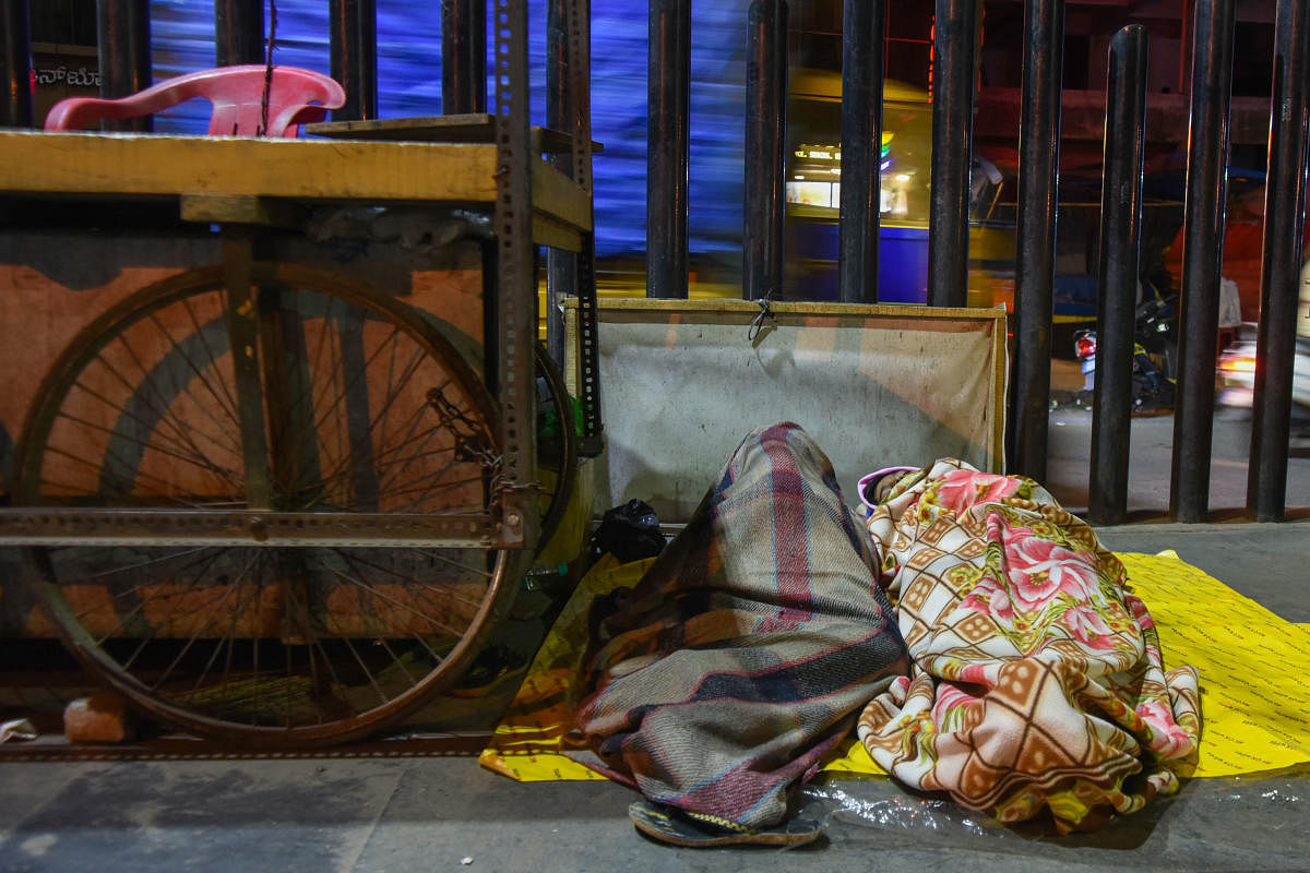 The Mysuru Road flyover and footpaths in its vicinity are used by many to spend cold nights. DH Photos/ Pushkar V