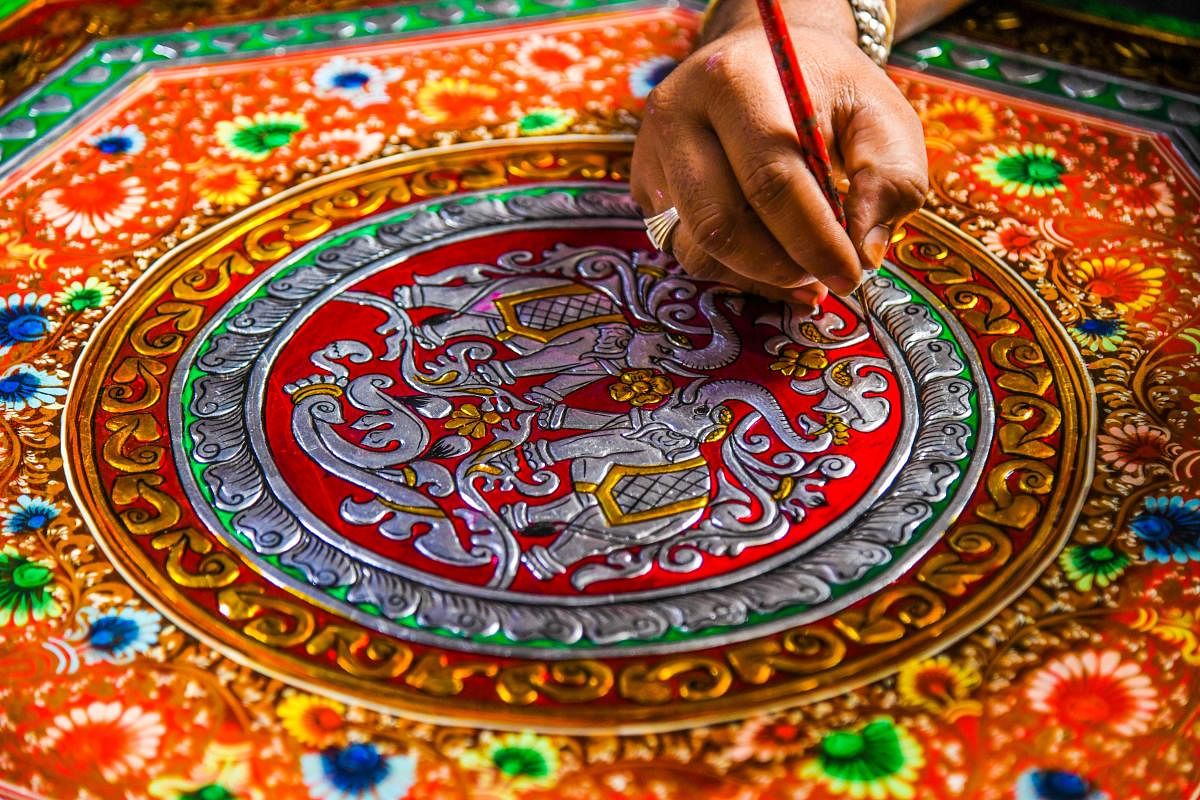A Kinnal artisan handpaints intricate designs on a new product.  