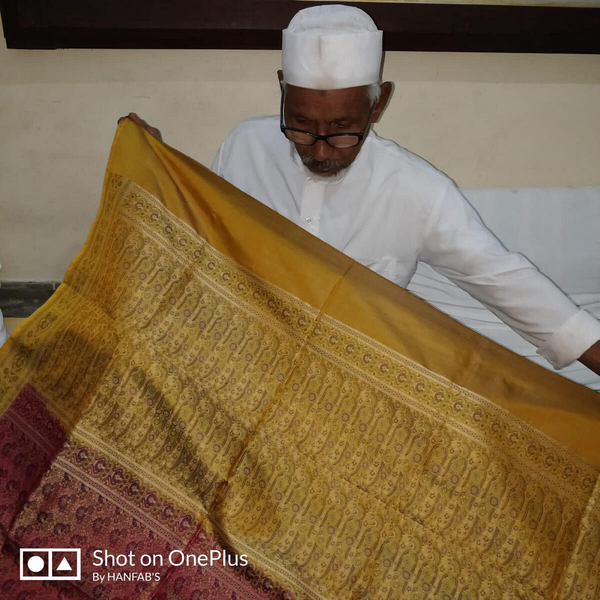 A weaver who works with Zillur Rahman displays a golden Banarasi sari. The sari took 48 days to complete.