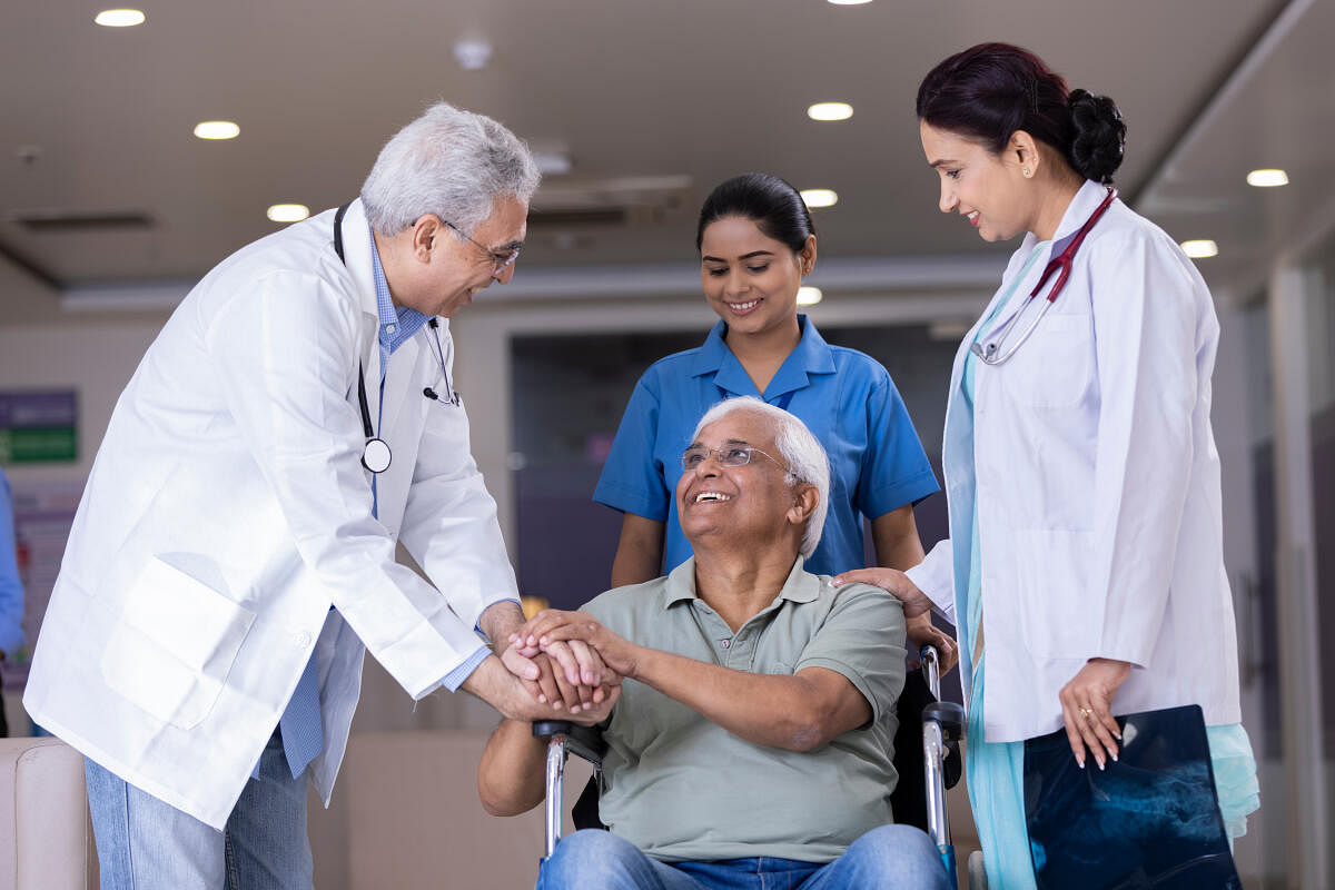 Doctors comforting disabled elderly patient in wheelchair at hospitalDoctors comforting disabled elderly patient.jpg