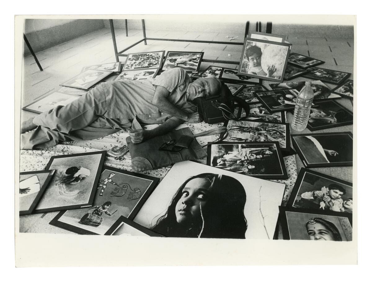 T S Satyan sleeping amidst his exhibition photographs (Unknown, 1999)