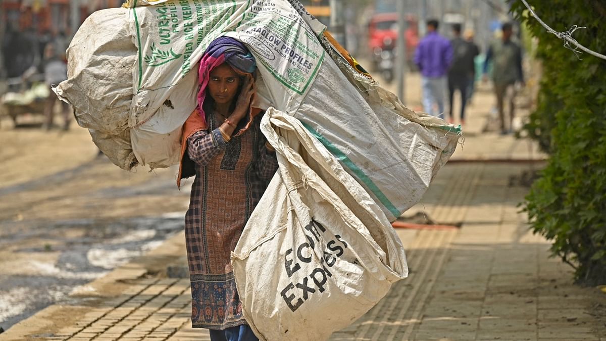A labourer carries a sack of garbage along a street in Srinagar on May 1, 2023. Credit: AFP Photo