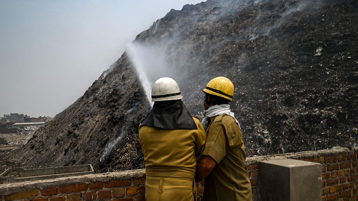 Dehi Fire Service (DFS) personnel spray water to douse a fire at the Bhlaswa landfill in New Delhi on May 4, 2022. Credit: AFP Photo