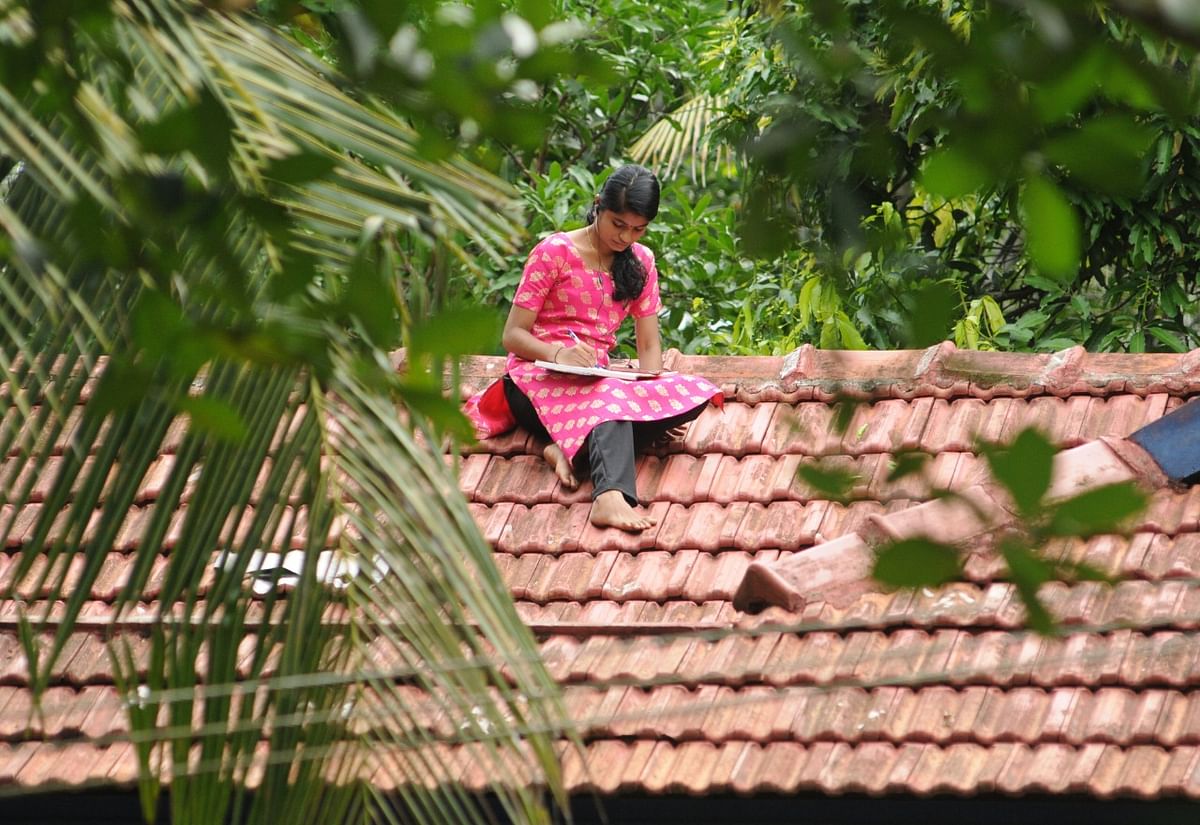 Namitha, a degree student of Malappuram, sitting on rooftop for good online connectivity for e-learning. Photo: Sakeer Hussain