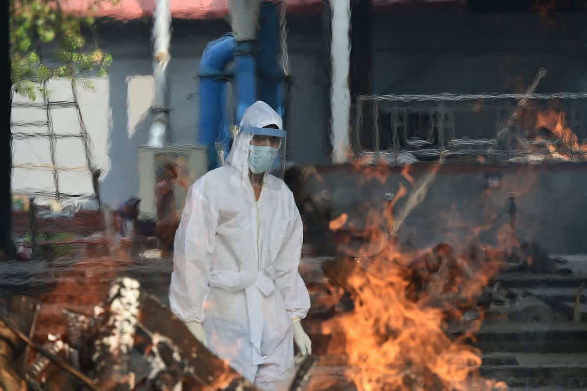 Chand Mohammad wearing a PPE kit cremates the body of a person who died of COVID-19, at a crematorium in New Delhi. Credit: PTI Photo